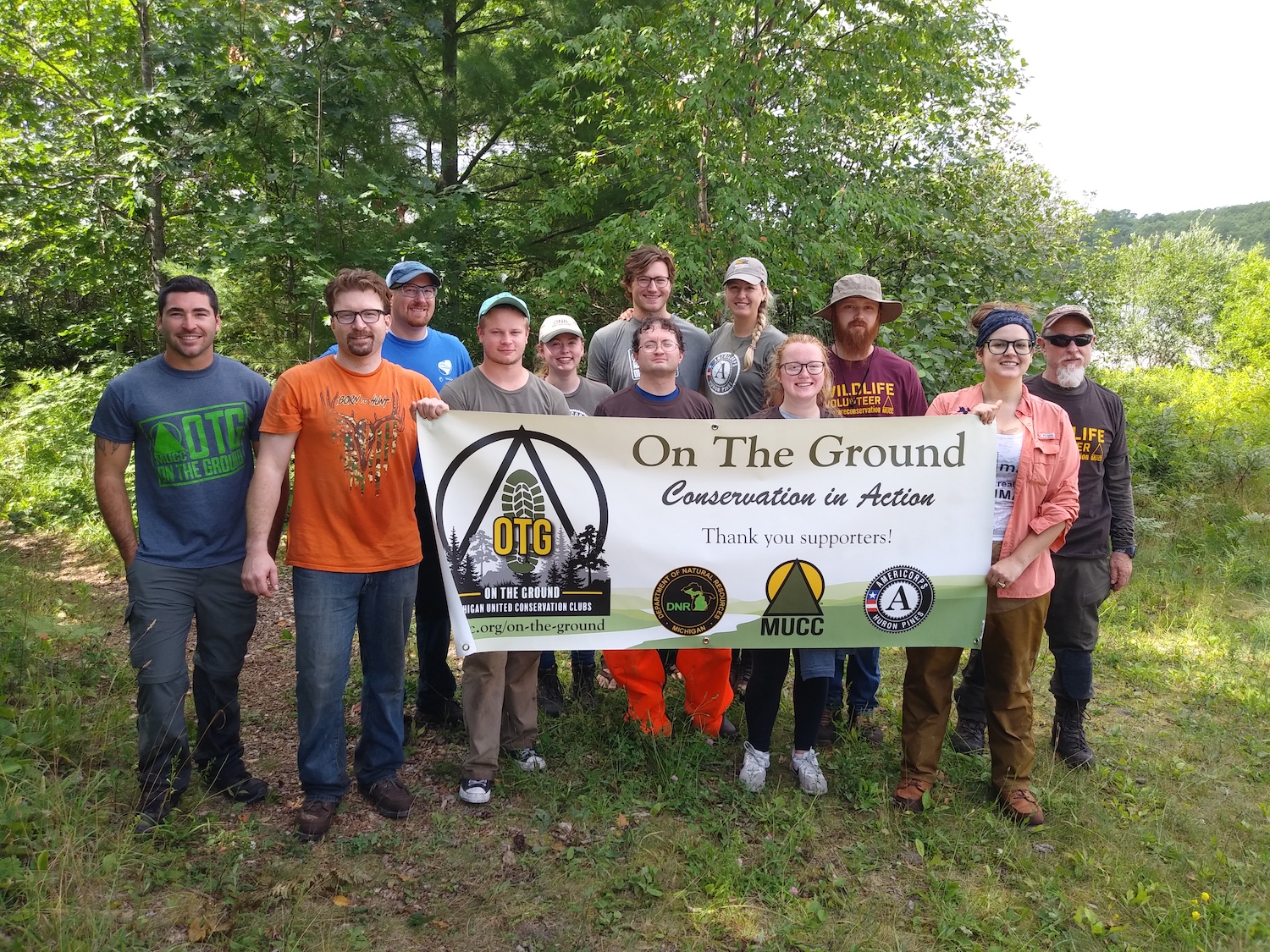 Volunteers gather for a picture, holding a sign that says "On the Ground"