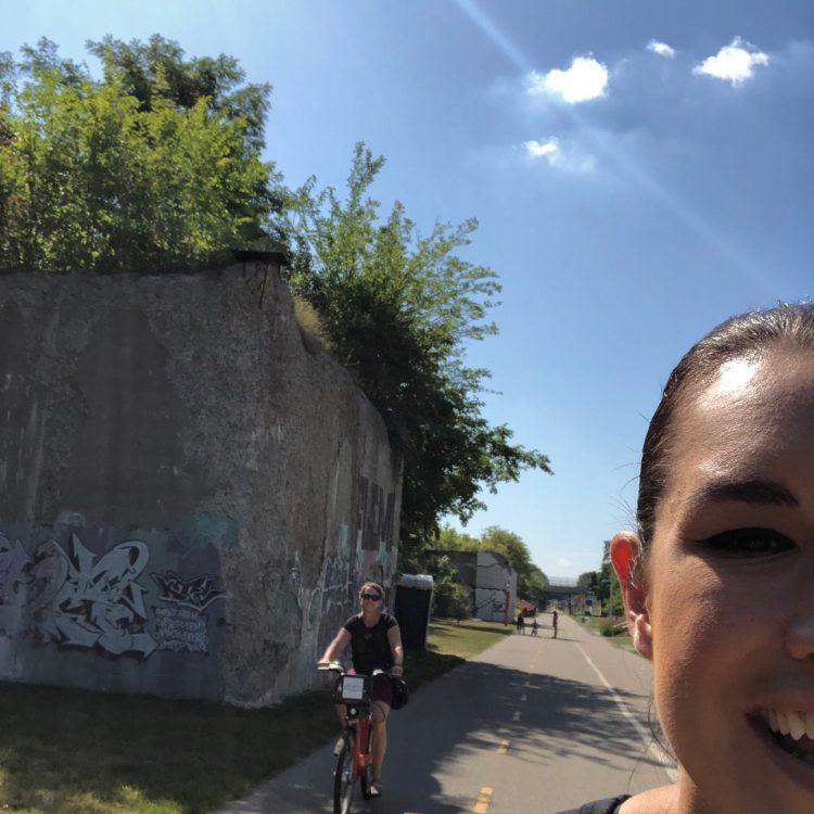A young woman takes a picture of herself along a concrete path