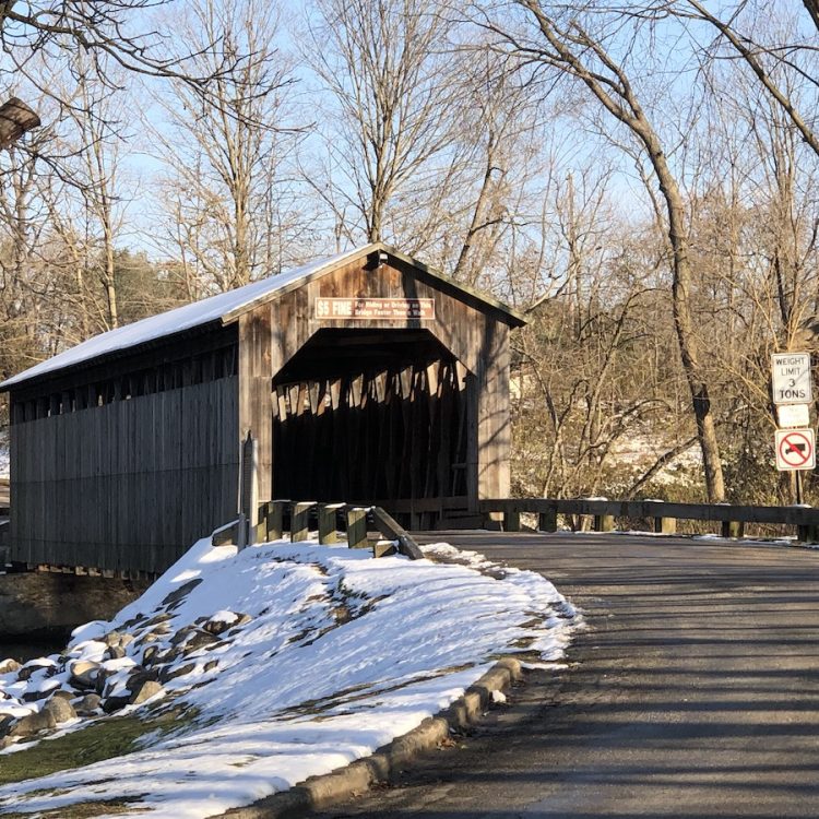 A wooden covered bridge over a road