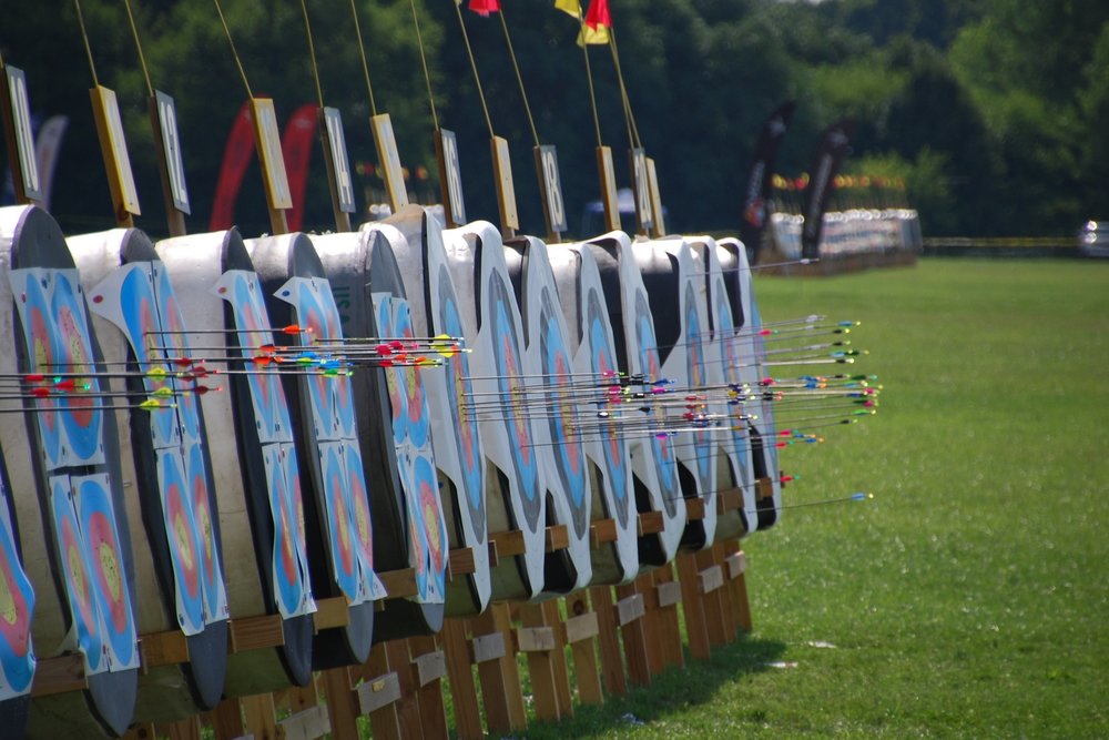 Side-view of a dozen archery targets sitting on grass